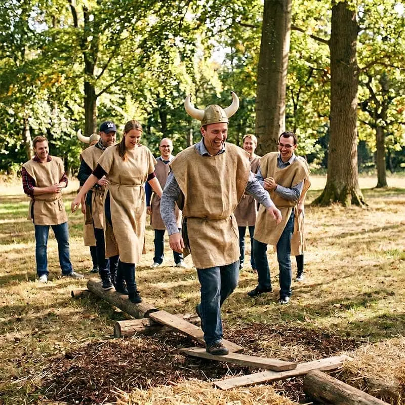 Gruppe deltager i teambuilding-aktivitet i skovmiljø.